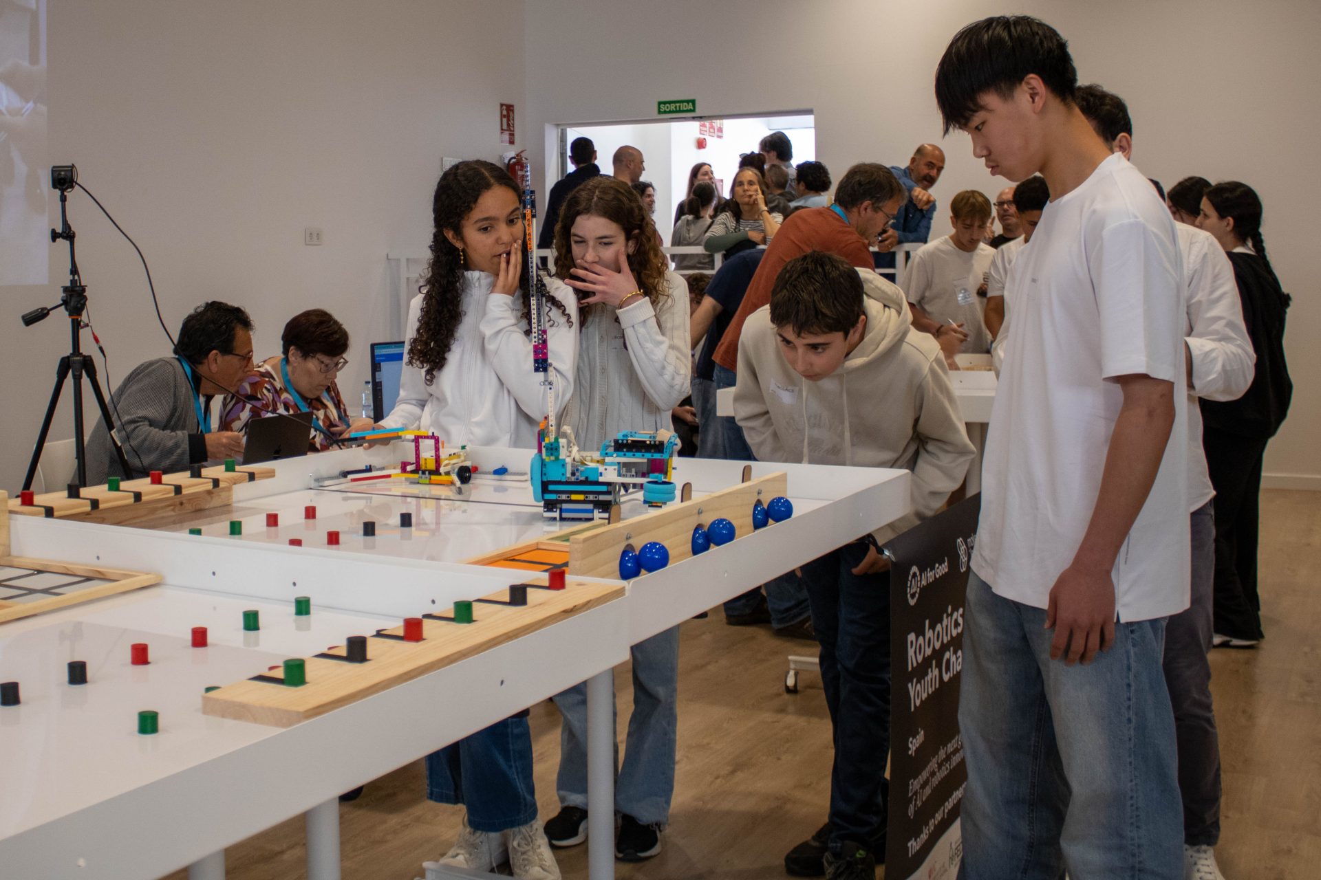 Alumnes observant i provant el funcionament d’un robot durant la competició